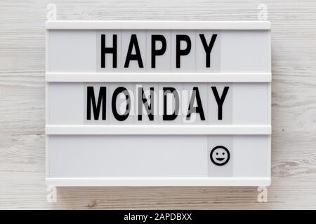 "Happy monday", Worte auf einem Leuchtkasten auf weißem Holzhintergrund, Draufsicht. Oben, von oben, flach. Nahaufnahme. Stockfoto