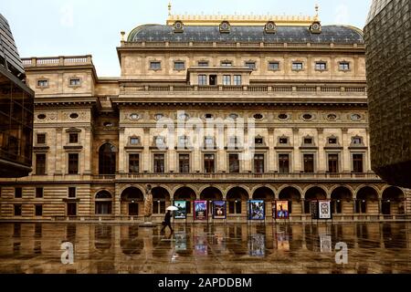 Mit einem Regenschirm gegen den Regen geht ein Mann durch die plaza, vorbei am Nationaltheater - Národní divadlo in Prag Stockfoto