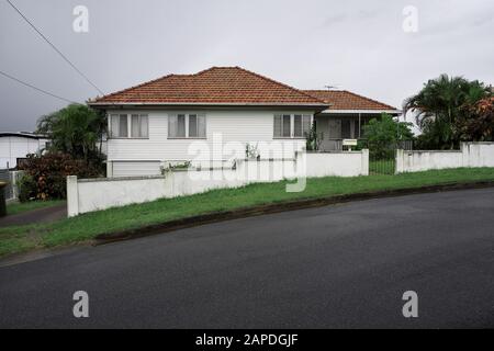 Tidy Post war Weatherboard House mit Fliesendach und niedrigem Stuckzaun, Seven Hills Brisbane Queensland, Australien. Stockfoto