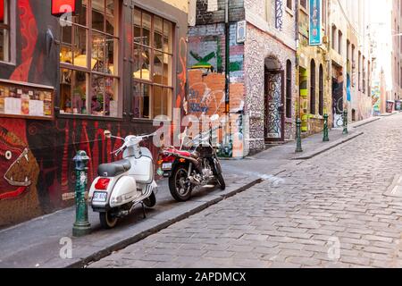 Eine weiße Vespa und ein Motorrad werden vor der Street Art im zentralen Viertel von Melbourne, Victoria, Australien geparkt. Stockfoto