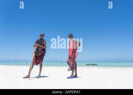 Sansibar, Tansania - 28. oktober 2019 : Zwei afrikanische Männer masai, gekleidet in traditioneller Kleidung, die in der Nähe des Ozeans am Strand Sansibar, Tanz, steht Stockfoto