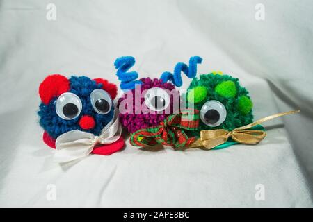 Nahaufnahme von drei wollig bunten Spielzeug mit googly Augen und Bänder auf einem weißen Tuch Stockfoto