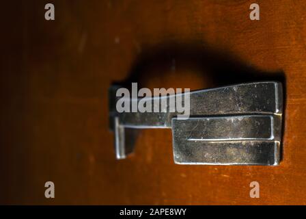 Nahaufnahme eines Metallstückes, das auf eine gestellt ist Braune Holzoberfläche Stockfoto
