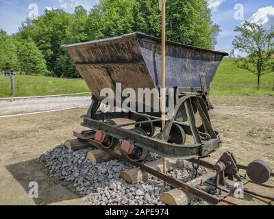 Alte Grubenwagen auf Schienen am Tag mit einem Gras Feld im Hintergrund Stockfoto