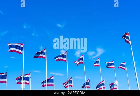 Viele thailändische Flaggen winken oben auf dem Fahnenmast gegen den blauen Himmel. Die thailändische Flagge wurde auf den Fahnenmast gezogen. Rotes, blaues und weißes Farbrechteck Stockfoto