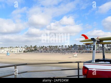 HUNTINGTON BEACH, KALIFORNIEN - 22. JANUAR 2020: Surfbrett auf Lifeguard Truck Rack am Pier mit Strand und Stadt im Hintergrund. Stockfoto