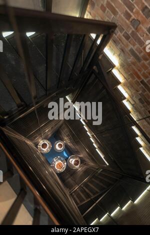 Riesige Pendelleuchten in der Mitte der Wendeltreppe mit roter Ziegelwand Stockfoto