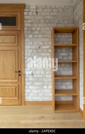 Eiche Tür und Bücherregal gegen weiße Ziegelwand Stockfoto