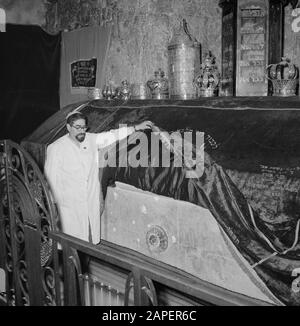 Israel 1964-1965: Jerusalem (Jerusalem), Kirchen und Klöster Beschreibung: Am Grabstein hebt der mutmaßliche Vormund/Gastgeber die Samtoberfläche, um eine ornamentierte Anmerkung zu zeigen: Das Grab befindet sich im Erdgeschoss und dient heute als Synagoge und Betraum. Der Grabstein ist mit einem Samttuch bedeckt und darauf Tora-Kronen aus Synagogenkreisen jüdischer Gemeinden, der Grabstein selbst hat Aufschriften und Verzierungen aus der Kreuzfahrerzeit. Die Letzte Abendmahlshalle und das Grab Davids befinden sich im selben Gebäude Datum: 1964 Ort: Israel, Jerusalem, Berg Zion Schlüsselwörter: Gräber, Stockfoto