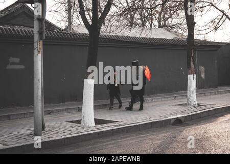 Vater und Sohn, die gemeinsam in den Straßen Pekings spazieren und während des Frühlingsfestes, am Tag des chinesischen Neujahrs, eine chinesische Flagge tragen Stockfoto