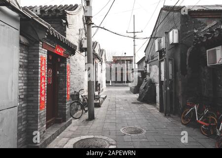 Dekorierte Straße/Hutong/kleine Gasse in Peking während des chinesischen Neujahrs, auch als Frühlingsfest bezeichnet. Mit Fahrrädern, alten Gebäuden Stockfoto