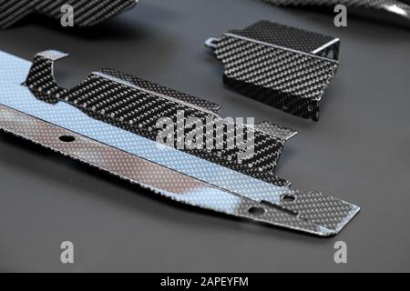 Nahaufnahme an den Außenelementen eines Autos aus Carbonfaser aus verflochtenen schwarzen und grauen Farben aus hochbelastenden Garnen für die Herstellung von Licht und Stockfoto