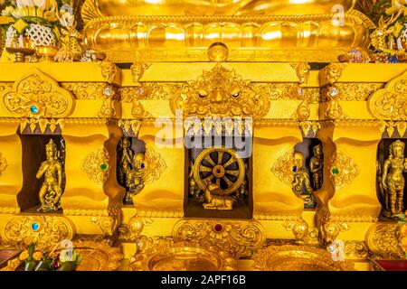 Dekoration und der Name in thailändischer Sprache am Fuß der goldenen sitzenden Buddhastatue im Wat Phra That Doi Phra Chan auf der Spitze des Berges in Mae Tha D Stockfoto