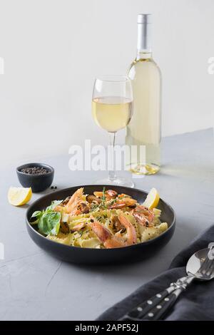 Nudelreginelle mit Meeresfrüchten, Garnelen, Muscheln, Weißwein auf grauem Steintisch, Nahaufnahme. Traditionelles Gericht im italienischen Restaurant. Stockfoto