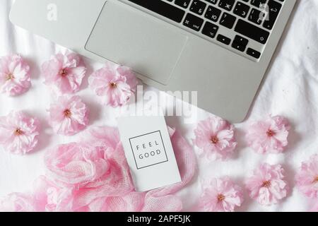 Flay Lay, Tischtisch mit Blick auf die Oberseite. Femininer Schreibtischrahmen mit Sakura-Blumen auf weißem Hintergrund, Ideen, Notizen oder Plan-Schreibkonzept. Moc Stockfoto