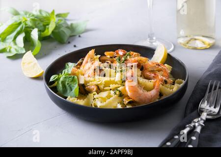 Pasta Spaghetti Reginelle mit Meeresfrüchten, Garnelen, Muscheln schwarze Platte mit Weißwein auf grauem Steintisch, Nahaufnahme. Traditionelles Gericht in italienischem Restaurant Stockfoto