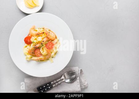 Pasta Spaghetti mit Meeresfrüchten, Garnelen reginelle weiße Platte am grauen Stein Tabelle, Ansicht von oben. Traditionelles Gericht in Italienisch. Platz für Text. Stockfoto