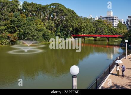 Osaka, JAPAN - 16. OKTOBER 2019: Der Blick auf den Kawazokoike Teich mit Springbrunnen und die rote Brücke im Tennoji Park von Osaka. Japan Stockfoto