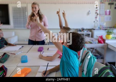 Gruppe von Schulkindern, die ihre Hände in einem Schulunterricht heben Stockfoto