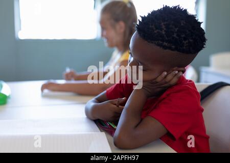 Der Schuljunge sitzt an einem Schreibtisch in einem Klassenzimmer der Grundschule Stockfoto