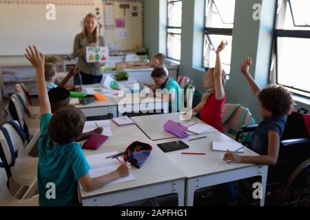 Gruppe von Schulkindern, die ihre Hände in einem Schulunterricht heben Stockfoto