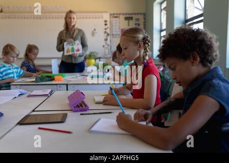 Schulmädchen sitzen an Schreibtischen in einem Schulunterricht Stockfoto