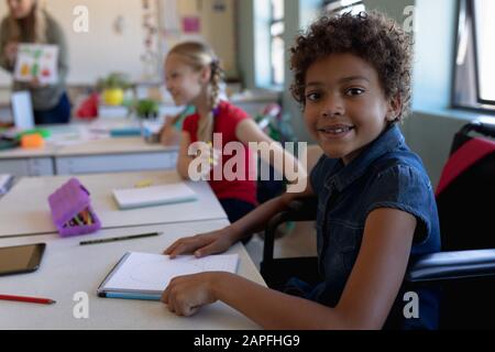 Schulmädchen sitzt im Rollstuhl in einem Schulunterricht Stockfoto