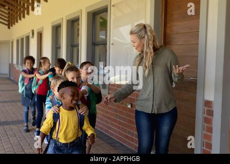 Lehrerin mit langen blonden Haaren, die eine Gruppe von Schülern an einer Grundschule führt Stockfoto