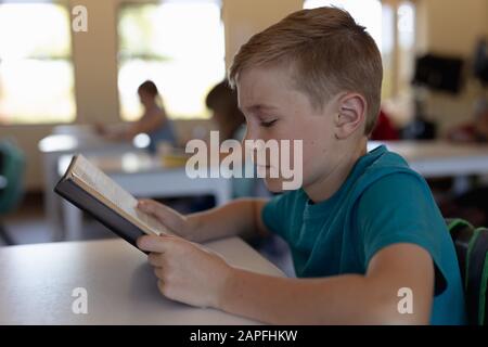 Der Schuljunge sitzt an einem Schreibtisch in einem Klassenzimmer der Grundschule Stockfoto