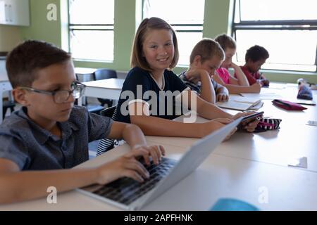 Gruppe von Schulkindern, die an Schreibtischen in einem Schulunterricht sitzen Stockfoto