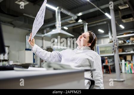 Der ernsthafte Labortechniker sitzt am Tisch und hat einen verwackelten Hintergrund aus Kohlenstoffgewebe Stockfoto