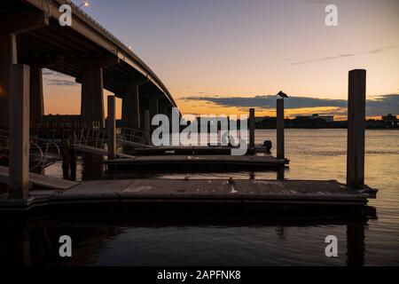 Silhouettierte Menschen, die ein Boot für eine Angeltour boardten, abseits eines Piers im Halifax River in Daytona Boarch, Florida, als die Sonne aufgeht. Stockfoto