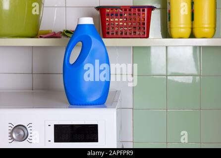 Blaue Flasche Waschmittel auf der Oberseite einer Waschmaschine in einer Waschküche Stockfoto