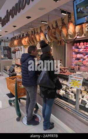 Ein Paar an einem Delicatessen-Schalter in einem lokalen Supermarkt in Italien Stockfoto