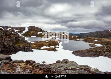 Typisch norwegische Landschaft mit schneebedeckten Bergen und Clear Lake in der Nähe der berühmten Aurlandsvegen (Bjorgavegen), Mountain Road, Aurland, Norwegen. Stockfoto