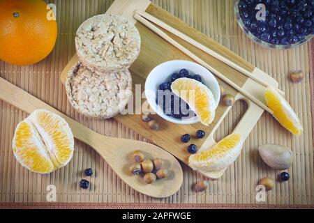 Flatley-Konzept gesunde Lebensmittel fünf Körner Laibe Avocadopfel Chokeberry orangefarbene Scheiben Nüsse auf einem Holzbambobushintergrund Stockfoto