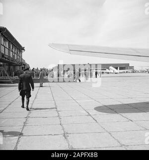 Flughafen Schiphol Beschreibung: Café-Terrasse Der weite Blick mit einem großen Hangar und einer geparkten Douglas DC-3 auf dem Flughafen Schiphol Datum: 1936 Standort: Amsterdam, Noord-Holland Schlüsselwörter: Außenansicht, Gebäude, Fluggesellschaften, Reisende, Flugzeuge, Flughäfen Name Der Einrichtung: Schiphol Stockfoto
