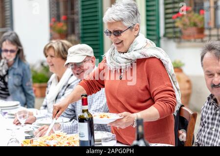 Frau, die Pasta beim Familienessen im Garten, Florenz, Italien serviert Stockfoto