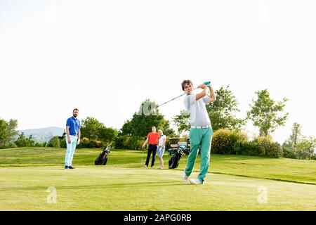 Freunde, die auf dem Golfplatz Golf spielen Stockfoto