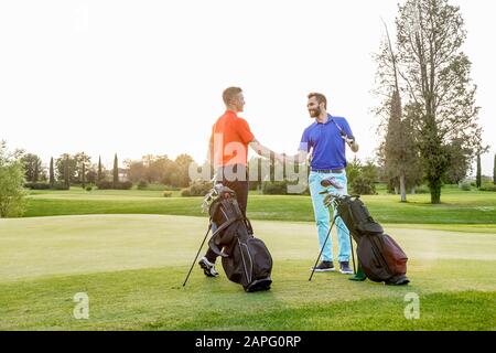 Freunde schütteln die Hände auf dem Golfplatz Stockfoto