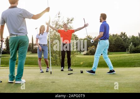 Freunde, die auf dem Golfplatz Golf spielen Stockfoto