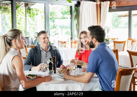Freunde sprechen am Esstisch im Restaurant Stockfoto