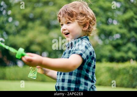 Kleinkind spielt mit Seifenblasen im Park Stockfoto