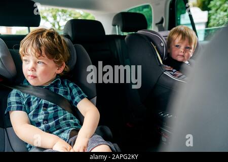 Brüder reiß auf Kinderautositze auf dem Rücksitz eines Familienautos. Stockfoto