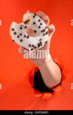 Hand, die einen weißen Donut mit Schokoladenchips hält Stockfoto