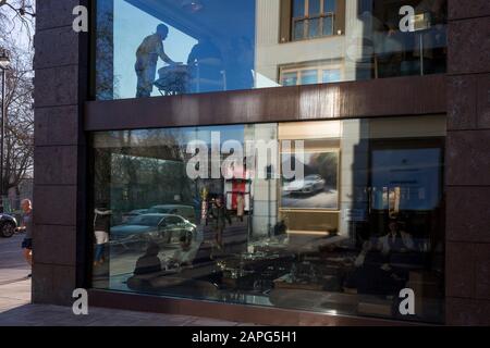 Mit einer Porsche-Luxusauto-Anzeige, die sich im Fenster widerspiegelt, besucht ein Restaurantkellner am 20. Januar 2020 die Kunden eines Ecktisches in London, England. Stockfoto