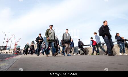London, Großbritannien - 1. APRIL 2016: Pendler und Büroangestellte, die während ihrer Hauptverkehrszeit die London Bridge überqueren. Stockfoto