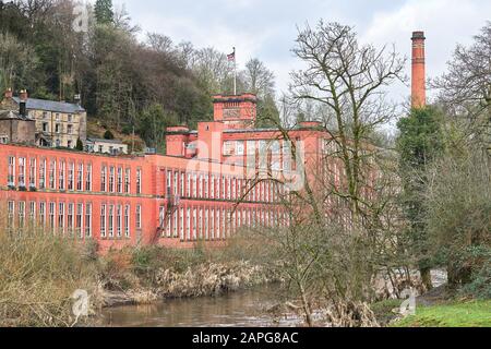 Sir Richard Arkwright's Masson Mill, eine Baumwollfabrik, die im 18. Jahrhundert in orangefarbenem rotem Backstein neben dem Fluss Derwent in Matlock Bat gebaut wurde Stockfoto