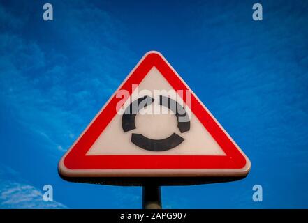 Dreiecksschild Am Kreisverkehr gegen blauen Himmel Stockfoto