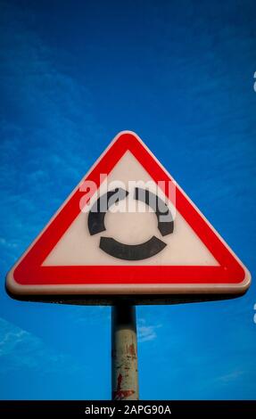 Dreiecksschild Am Kreisverkehr gegen blauen Himmel Stockfoto
